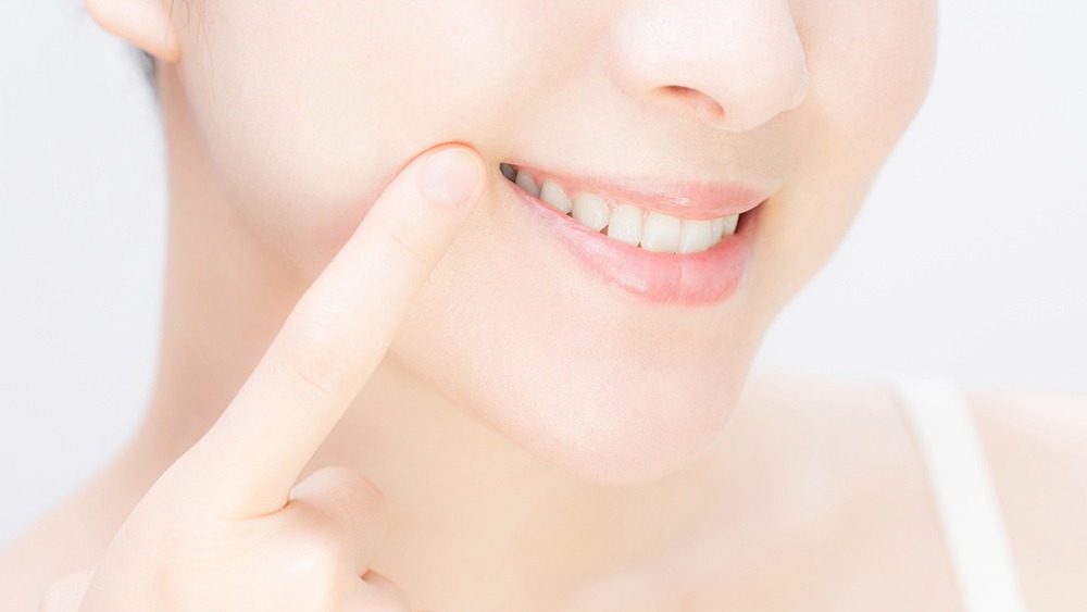 白い歯で笑う女性の口元のイメージ写真