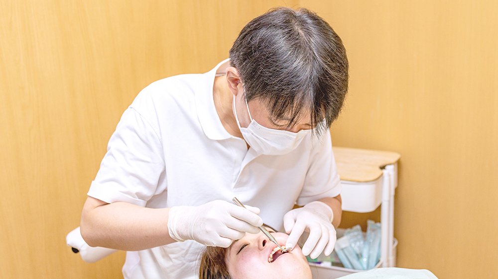 歯科医師が患者の口腔内をミラーで確認している診察風景